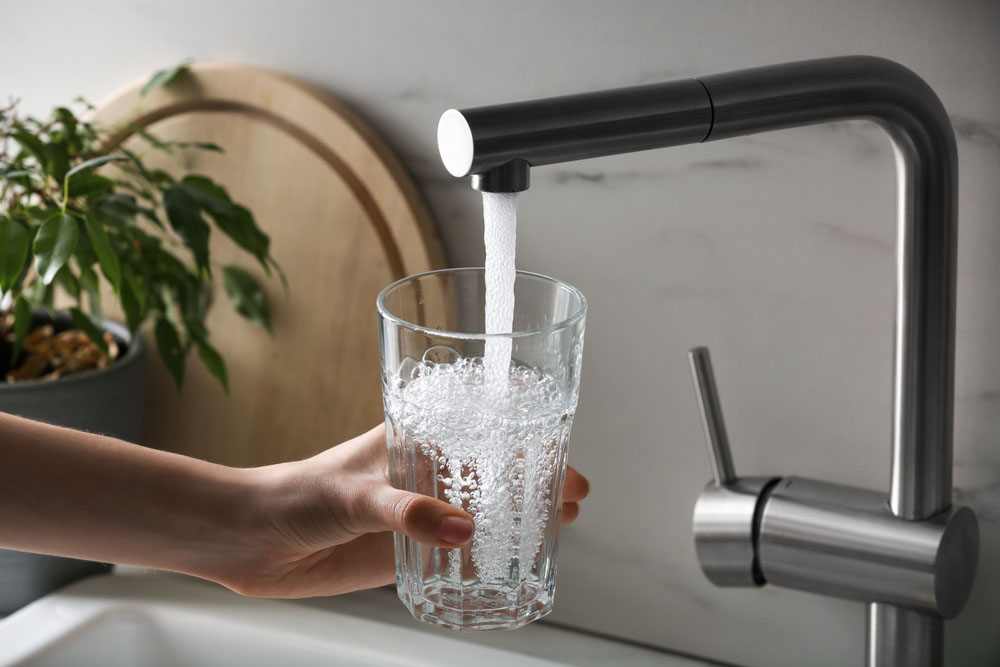 a drinking glass being filled with water from the tap